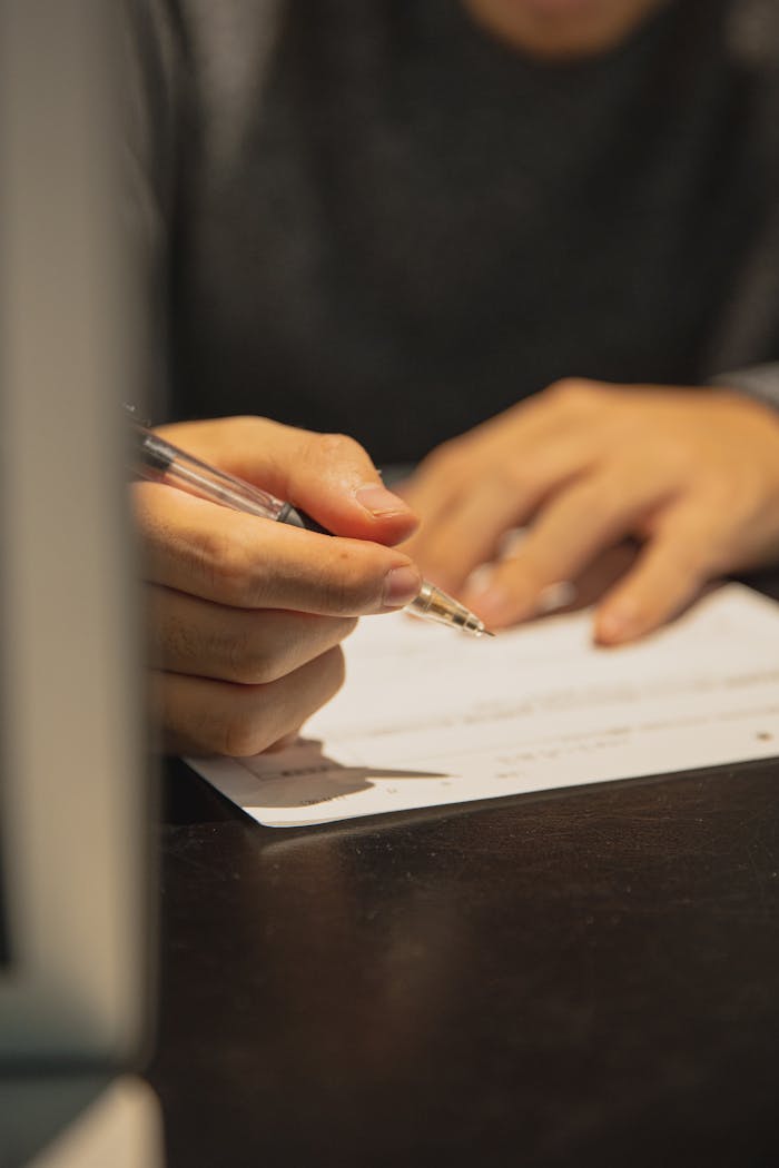 services-05 A person writing on a document at an office desk, focused on paperwork.