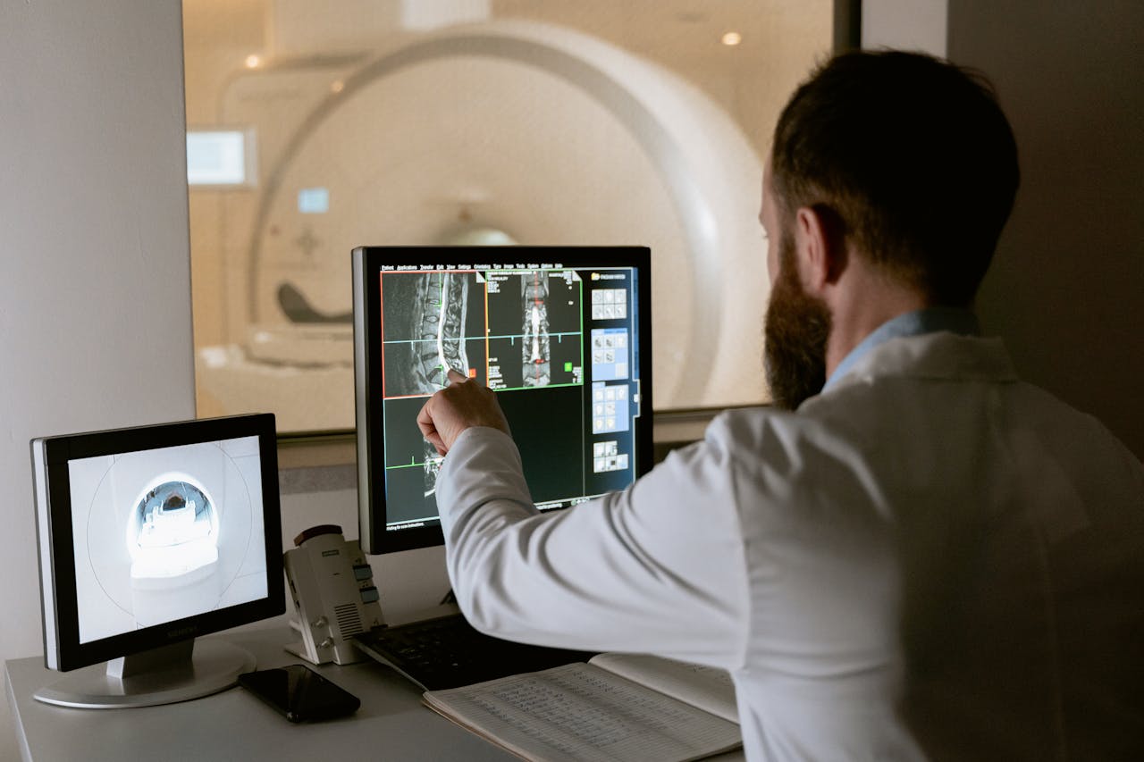 services-bg Medical professional reviewing MRI scans on computer screens for diagnostic purposes.