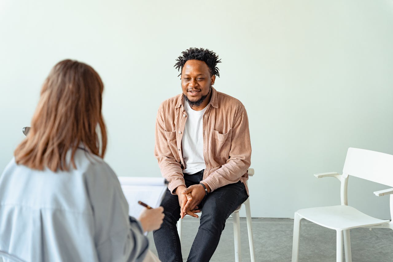 who-we-are A therapy session in a modern office setting with a counselor and a client engaged in conversation.