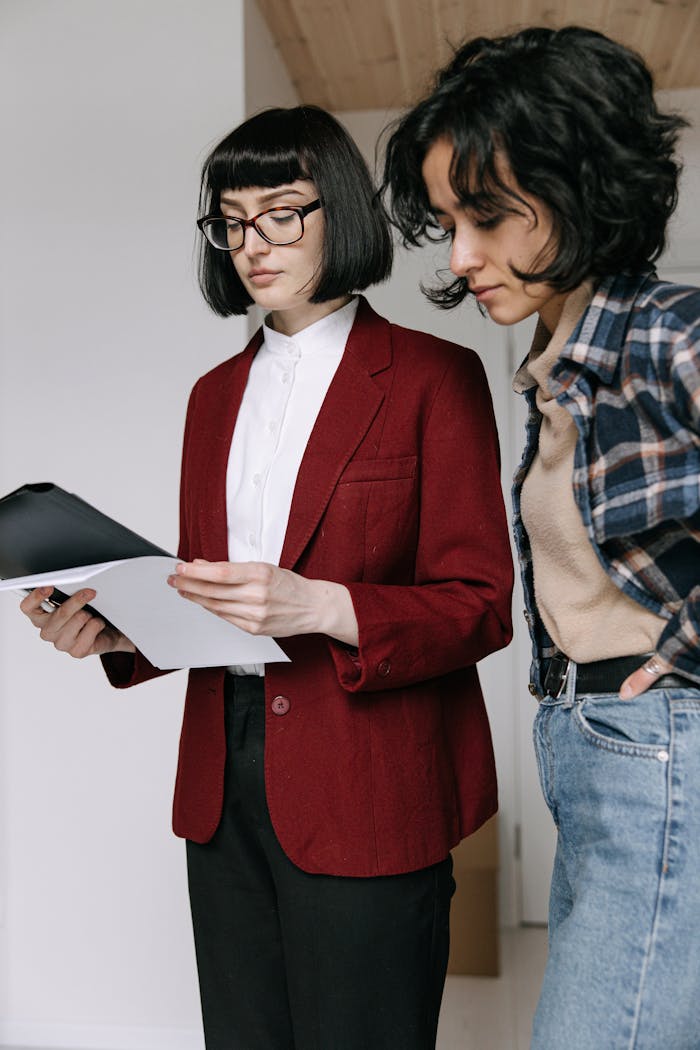 about-us Two women reviewing documents potentially related to real estate decisions indoors.
